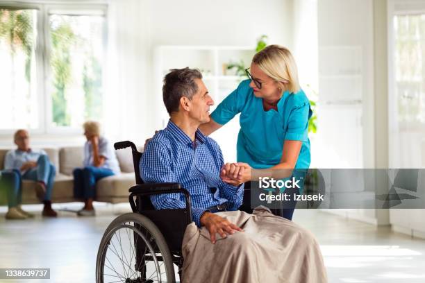 Cheerful Home Nurse And Senior Man In Retirement House Stock Photo - Download Image Now