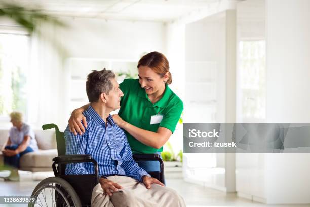Cheerful Social Worker Supporting Senior Man Stock Photo - Download Image Now - 70-79 Years, A Helping Hand, Adult