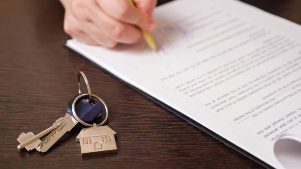 man signs apartment purchase contract near keys at table - rental stockfoto's en -beelden