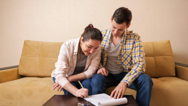 hombre y mujer firman contrato de alquiler de apartamento en mesa de café - real estate mortgage document key contract fotografías e imágenes de stock