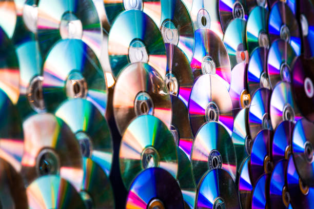 Abstract image depicting a large group of CDs (compact discs) glittering and shining in the sun, producing a rainbow color effect.