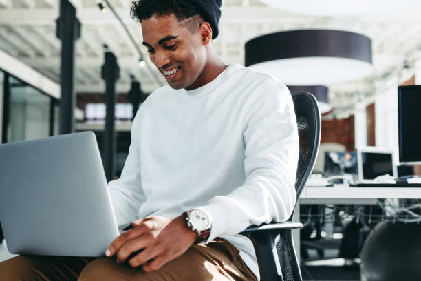 istock Smiling businessman working on a laptop in a modern office 1338648547