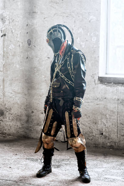 istock Terrifying post apocalyptic human creature, person survived in poisoned by pollution, post nuclear catastrophe world wearing leather jacket with chains and gas mask. Holds machete 1338649682