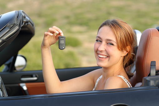 Happy convertible car driver showing key