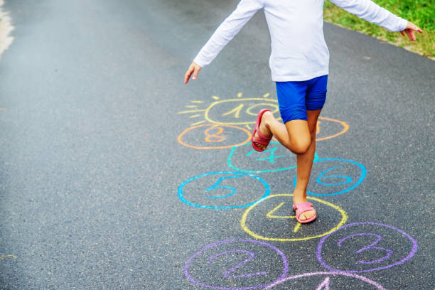 bambini che saltano classici sul marciapiede. messa a fuoco selettiva. - little girls sidewalk child chalk foto e immagini stock