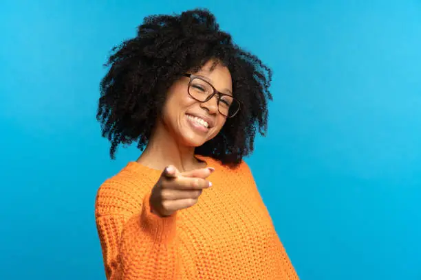 Photo of Cheerful african american girl point finger choosing you smiling. Job position offer, career concept