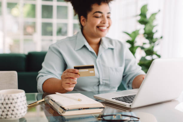 Woman doing online shopping using credit card and laptop Woman at home doing online shopping with credit card and laptop. Female making online payment using credit card for shopping on ecommerce website. spending money stock pictures, royalty-free photos & images