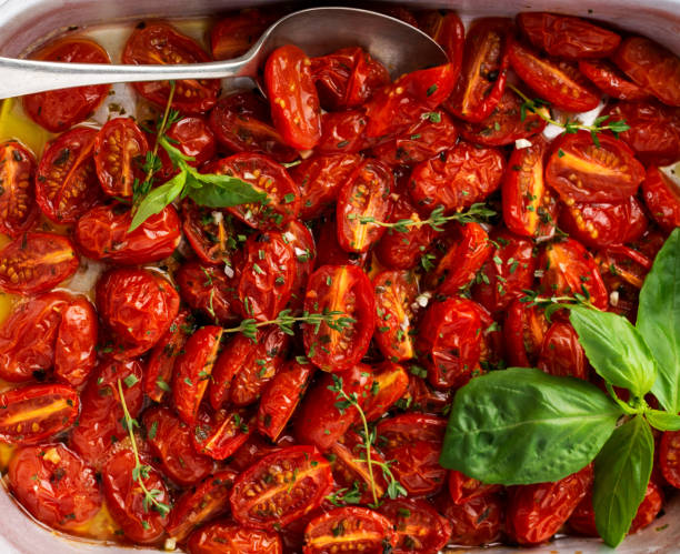 istock Baked cherry tomato with garlic, thyme and basil in old baking pan on concrete vintage background. Top view 1338669393