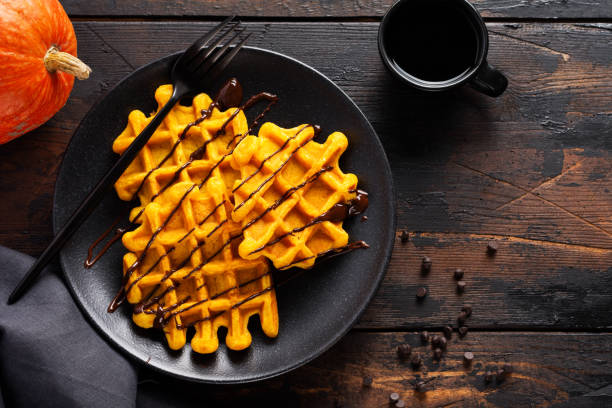 Pumpkin waffles with chocolate and sugar powder on dark old background. Top view