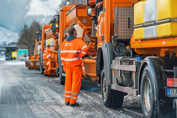 Group of bright orange highway maintenance trucks ready on winter road Liptovsky Hradok, Slovakia - February 12, 2020: Group of bright orange highway maintenance trucks with de icing salt getting ready on winter, snow covered road winterdienst stock pictures, royalty-free photos & images