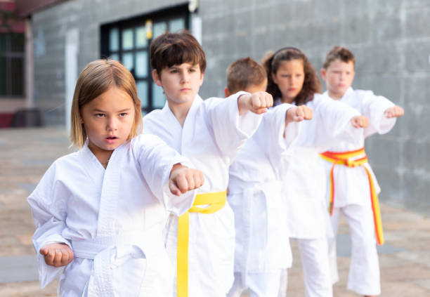 istock Young children in kimono perform techniques karate on city street 1338673745