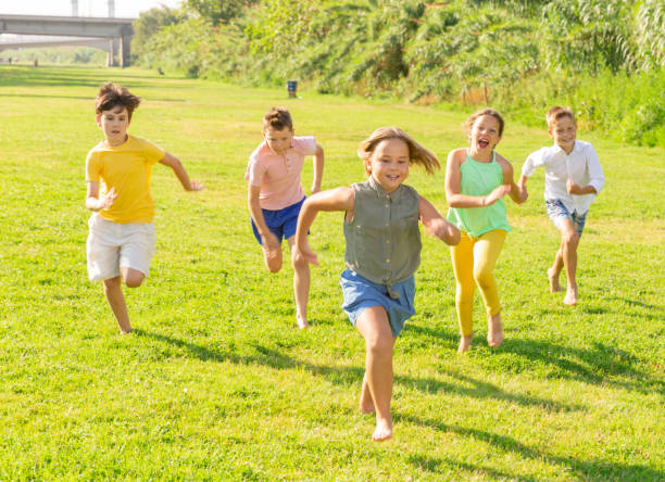 istock Group of five happy children jogging in a park 1338673787