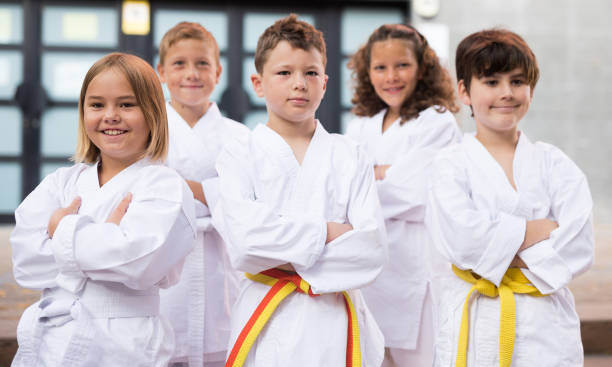 gruppo di scolari che praticano il karate nel cortile della scuola - arte marziale foto e immagini stock