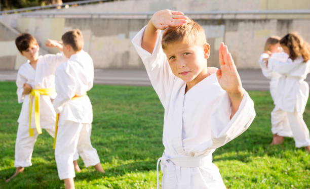istock Preteen boy practicing karate during group class on green lawn 1338673835