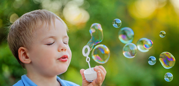 the kid closed his eyes with pleasure playing with soap bubbles