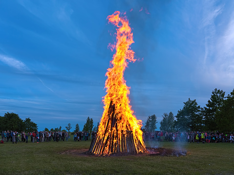 Kuressaare, Saaremaa island, Estonia - June 23, 2017: Traditional large bonfire to celebrate the Jaanipaev (Jaan's Day). This Estonian public holiday corresponds to the English Midsummer Day. Many unknown people stand around the bonfire.