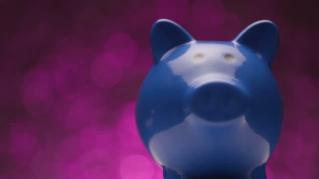 blue piggy bank being presented in front of pink lights backgrounds, moving right and left and spinning