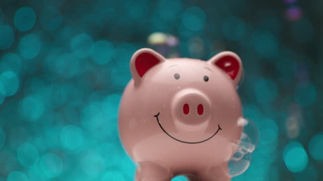 project video showing piggy bank with soap bubbles in front of blue lights background being presented and moving