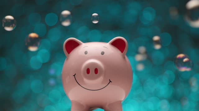 pink piggy bank in front of blue lights backgrounds with soap bubbles turning and spinning while being presented