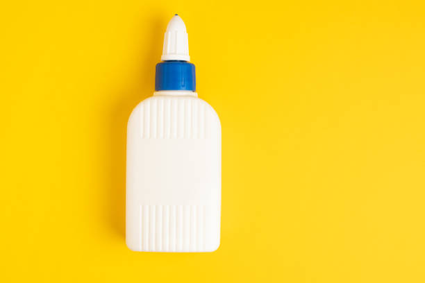 pega botella blanca de plástico sobre un fondo amarillo. - glue bottle isolated art and craft fotografías e imágenes de stock