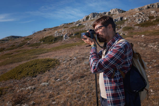 istock Young man taking photographs with digital camera in a mountains. 1338685667