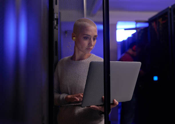aufnahme einer jungen ingenieurin, die in einem serverraum arbeitet - data center computer programmer women stock-fotos und bilder