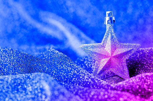 Christmas ornament (christmas star) on a sparkling textile background with beautiful bokeh. Space for copy.