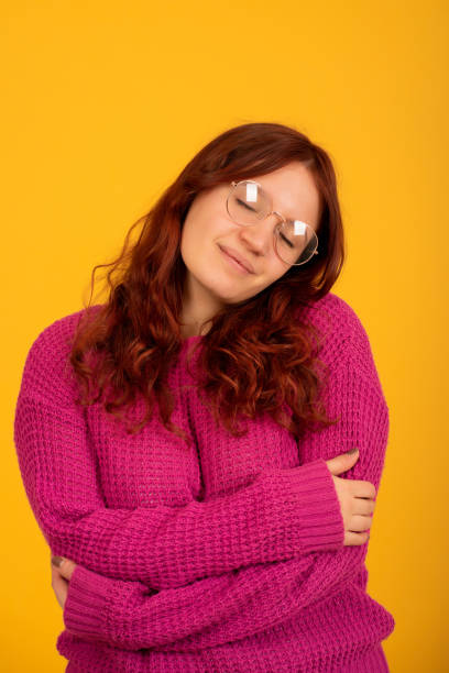istock Woman embracing to herself while standing on an isolated background. 1338688177