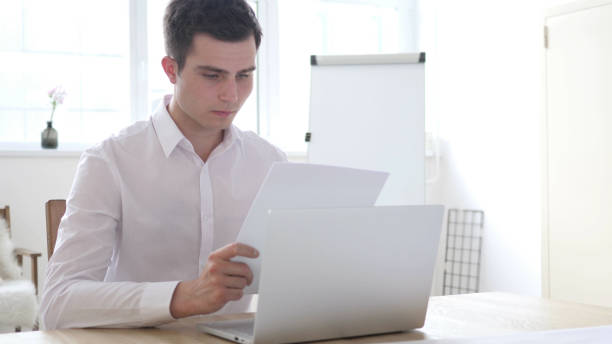 empresario leyendo documentos en office - 16490 fotografías e imágenes de stock