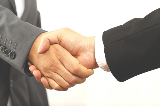 Business people shaking hands in the office. Photo of one cheerful businessman and one happy businesswoman handshaking.