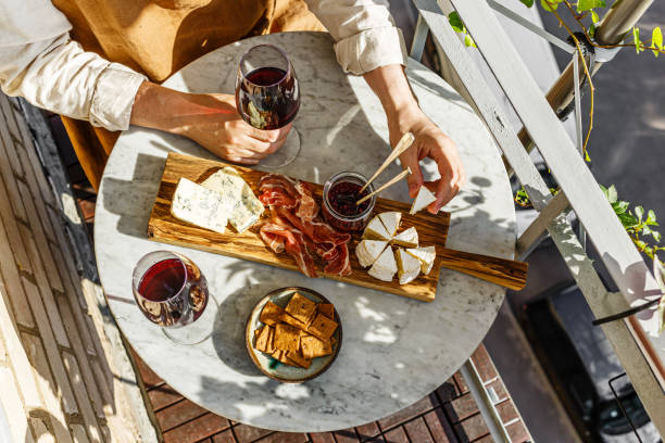 antipasto vario tagliere di formaggi con formaggio a pasta molle, salsa di frutta e vino rosso sul tavolo di marmo per una piccola festa nella giornata di sole estivo - cheese platter foto e immagini stock