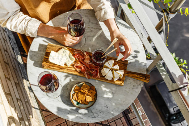 urozmaicona przystawka deska serów z miękkim serem, sosem owocowym i czerwonym winem na marmurowym stole na małą imprezę w letni słoneczny dzień - cheese platter zdjęcia i obrazy z banku zdjęć