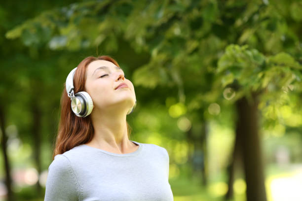 donna che indossa le cuffie meditando ascoltando l'audioguida - toll free audio foto e immagini stock