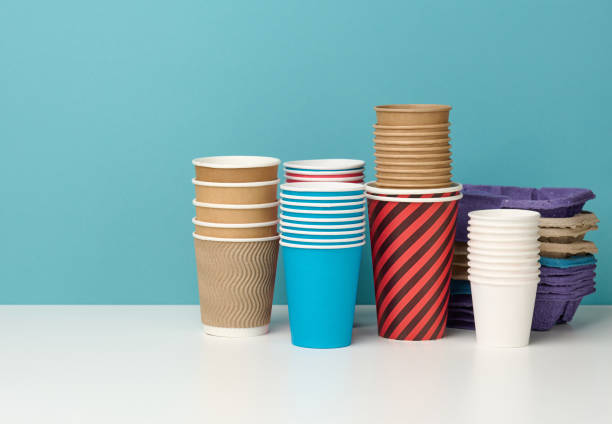 pila di bicchieri monouso multicolore e stand su tavolo bianco, sfondo blu - disposable cup cup stack blue foto e immagini stock