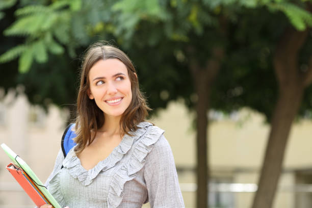 istock Happy pensive student looking at side in the street 1338690317