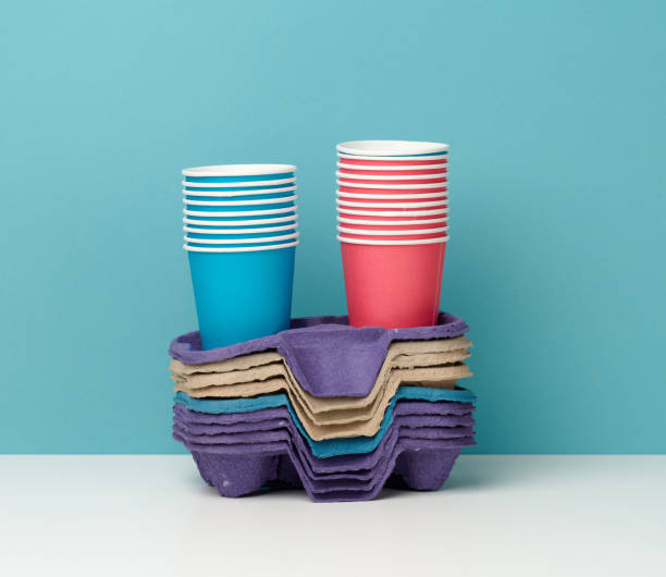 pila di bicchieri monouso multicolore e stand su tavolo bianco, sfondo blu - disposable cup cup stack blue foto e immagini stock