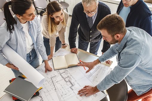 College professor examining blueprint with group of his students.