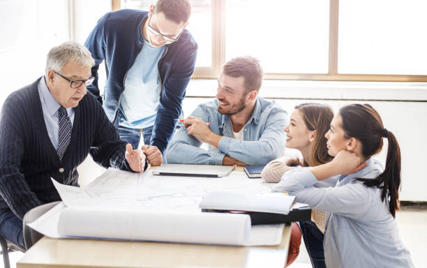 istock College professor examining blueprint with group of his students. 1338691810