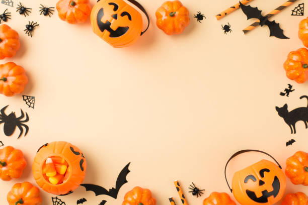 istock Top view photo of halloween decorations pumpkin baskets candy corn straws spiders web bats and black cat silhouettes on isolated beige background with empty space in the middle 1338691841