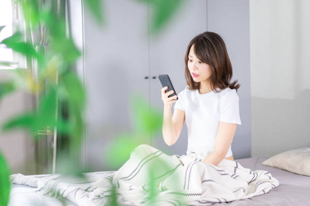 istock Young woman using her phone in bed 1338692152