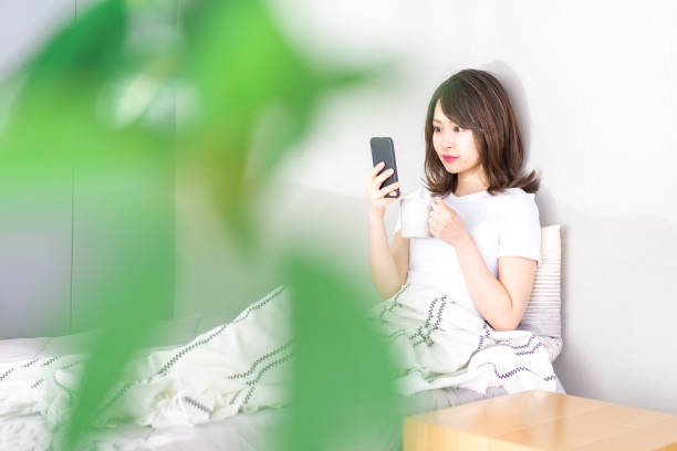 istock Young woman using her phone in bed 1338692160