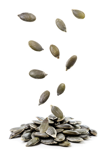 Peeled pumpkin seeds fall on a heap close-up on a white background. Isolated