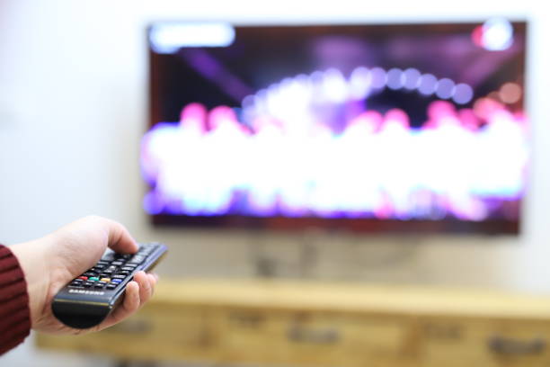 use the remote control to change channels on Television stock photo