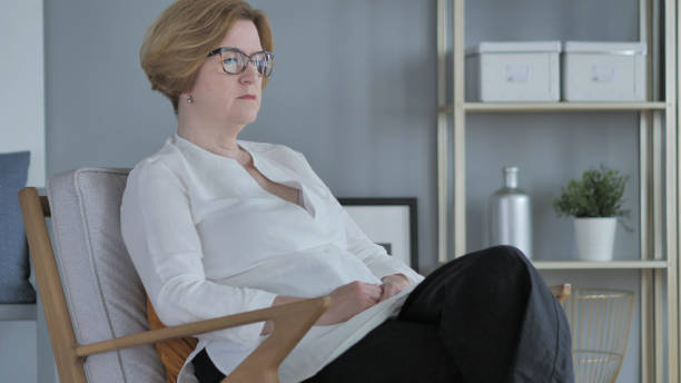 istock Old Woman Sitting on Couch in Bedroom 1338694642