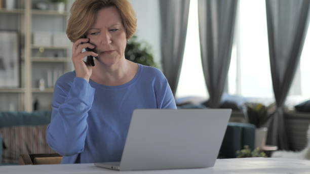 wütende alte frau, die über die arbeit am telefon diskutiert - 16642 stock-fotos und bilder