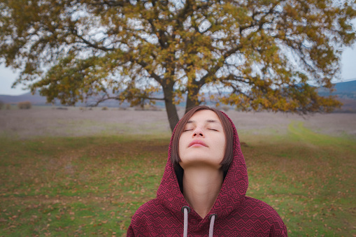 Portrait of a young asian woman in hoodie in the autumn nature. Outdoor atmospheric lifestyle portrait. Season and people