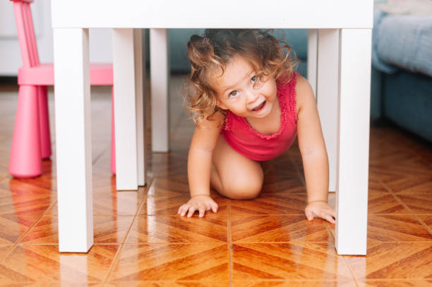 istock Little girl smiling playing under a table at home 1338698147