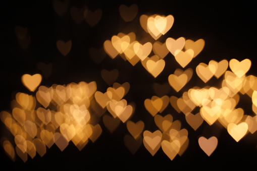 golden defocus lights in the shape of hearts on black background