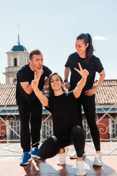 équipement de fitness de trois jeunes femmes sur une terrasse regardant la caméra - underwear men t shirt white photos et images de collection