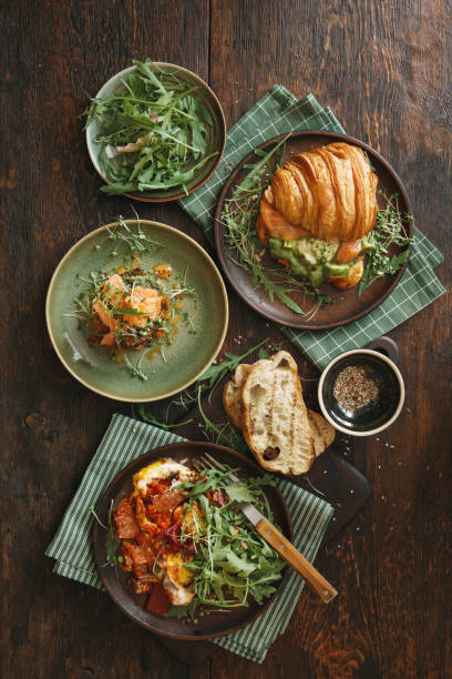 Healthy Meals for Breakfast Steak and eggs with salad. Zucchini fritters with cold-smoked salmon. Smoked salmon croissant sandwich. Flat lay top-down composition on wooden background. food styling stock pictures, royalty-free photos & images